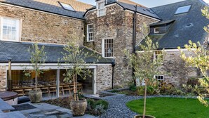 A stone building with a patio area, outdoor seating, and a well-maintained lawn. - Beautiful  villa for 19 people with hot tub, WIFI, TV, terrace and pets allowed (Newquay)