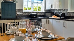 Une cuisine moderne avec des meubles blancs, un plan de travail noir et une fenêtre dotée d’un store bleu.