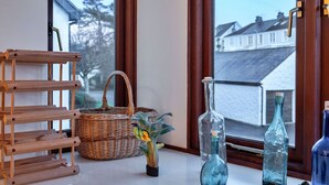 Een kamer met een houten rek, een rieten mand en glazen flessen op een tafel.