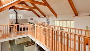 A spacious loft with exposed wooden beams, a kitchen area, and a balcony with a wooden railing. - Beautiful  villa for 6 guests with WIFI, terrace and pets allowed (Portloe)