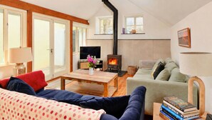 A cozy living room with a fireplace, a sofa, a coffee table, and a television. - Beautiful  villa for 6 guests with WIFI, terrace and pets allowed (Portloe)