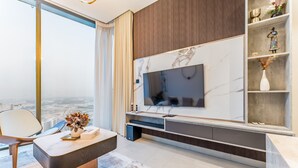 A modern living room with a large TV, a coffee table, and a city view.