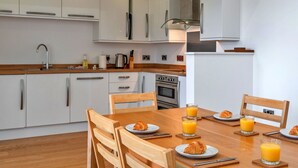 Cocina moderna con armarios blancos, encimera de madera y comedor con mesa dispuesta para el desayuno.