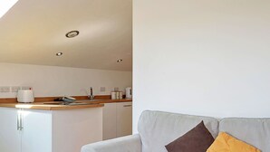A modern living room with a grey sofa and a kitchen area in the background. - Lovely apartment for 3 people with terrace (Bodmin)