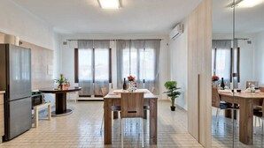 A modern kitchen with a dining area, large windows, and a mirrored wall. - Cozy Apartment 2 steps from the Railway Station (Chirignago-Zelarino)