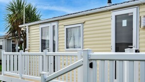 A row of mobile homes with white railings and a palm tree in the background. - Beautiful  villa for 6 people with pool, WIFI, terrace and pets allowed (Ruan Major)