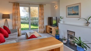 Ein Wohnzimmer mit einer Couch, einem Couchtisch, einem Fernseher und einem Kamin.