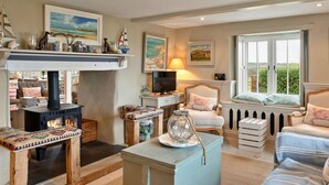 A cozy living room with a fireplace, comfortable seating, and artwork on the walls.
