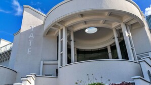 Un edificio con una entrada circular, un letrero que dice "TATE" y una escalera que conduce a un nivel superior.