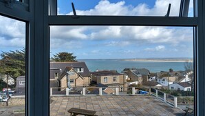 A view from a window overlooking a coastal town with houses, a beach, and a clear sky. - Beautiful apartment for 4 guests with WIFI (St Ives)