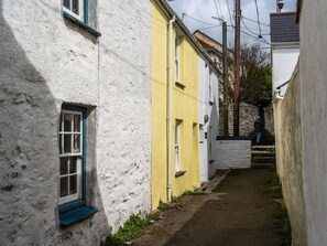 Une ruelle étroite, située entre deux bâtiments, avec un mur de pierre et un escalier menant à un bâtiment également en pierre.