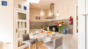 Una cocina moderna con comedor, que incluye una encimera blanca, sillas grises y luces colgantes.
