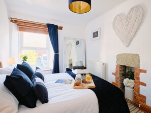 Ein Schlafzimmer mit einem Bett, einem Frühstücksbrett, einem Kamin und einer herzförmigen Dekoration an der Wand.