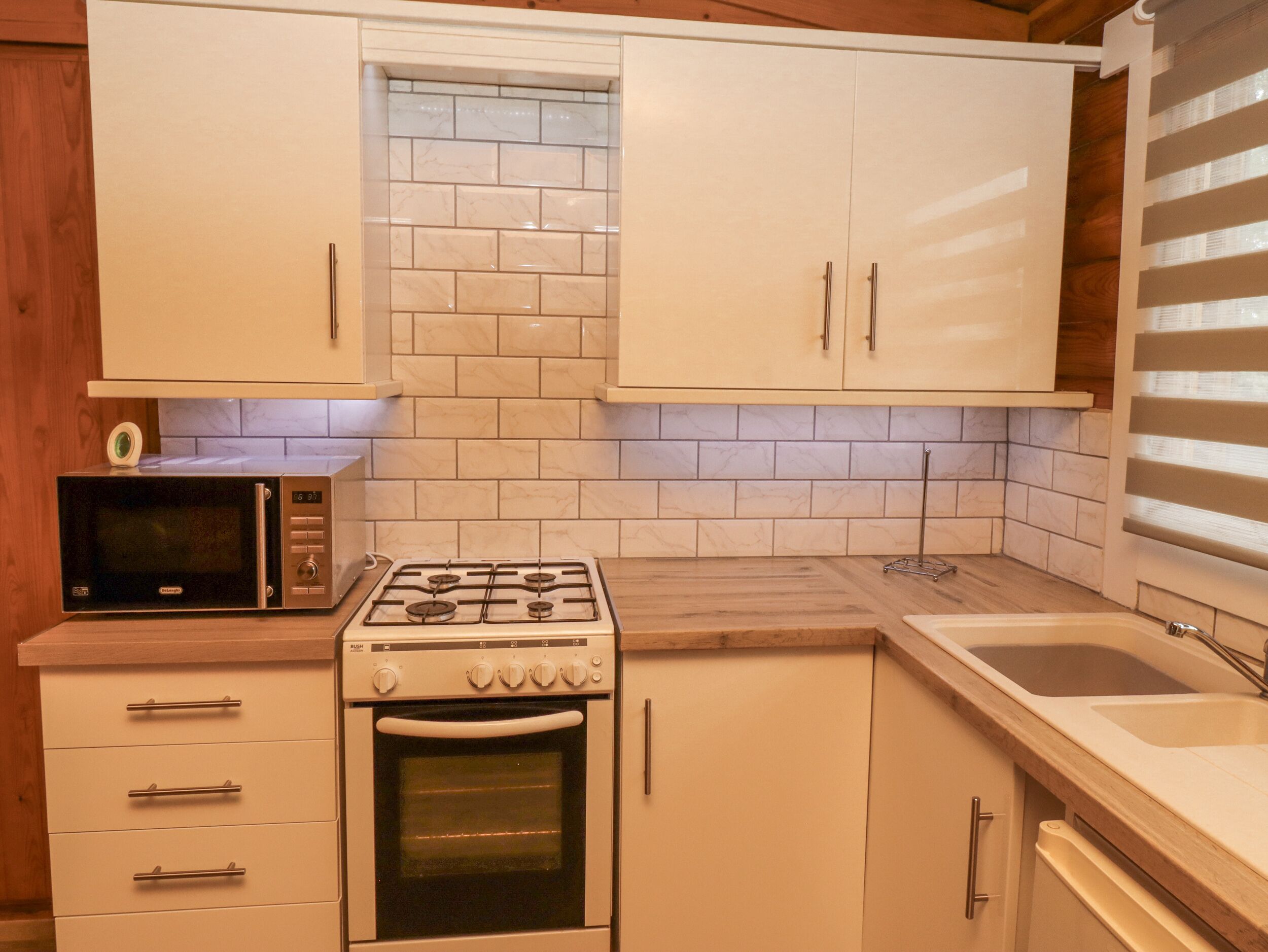 A compact kitchen with white cabinets, a microwave, a gas stove, and a built-in oven.