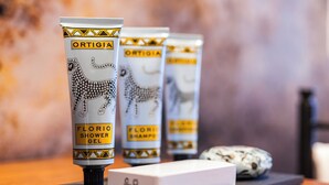 Três tubos de Ortigia Florio Shower Gel e duas caixas de Ortigia Shampoo sobre uma superfície de madeira.