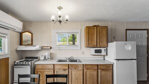 A kitchen with wooden cabinets, a white stove, a microwave, and a refrigerator.