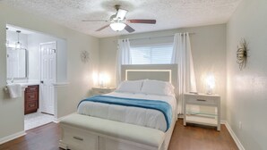 A bedroom with a bed, bedside tables, a ceiling fan, and a window with curtains.