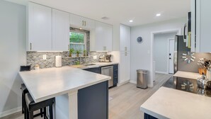 A modern kitchen with white cabinetry, a central island, and a backsplash with a mosaic tile design.