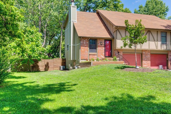 A two-story house with a red garage door, a chimney, and a well-maintained lawn.