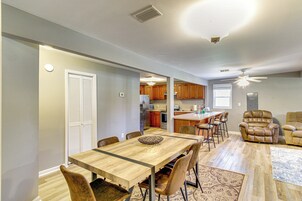 A spacious living room with a dining area, a kitchen, and a seating area with leather chairs.