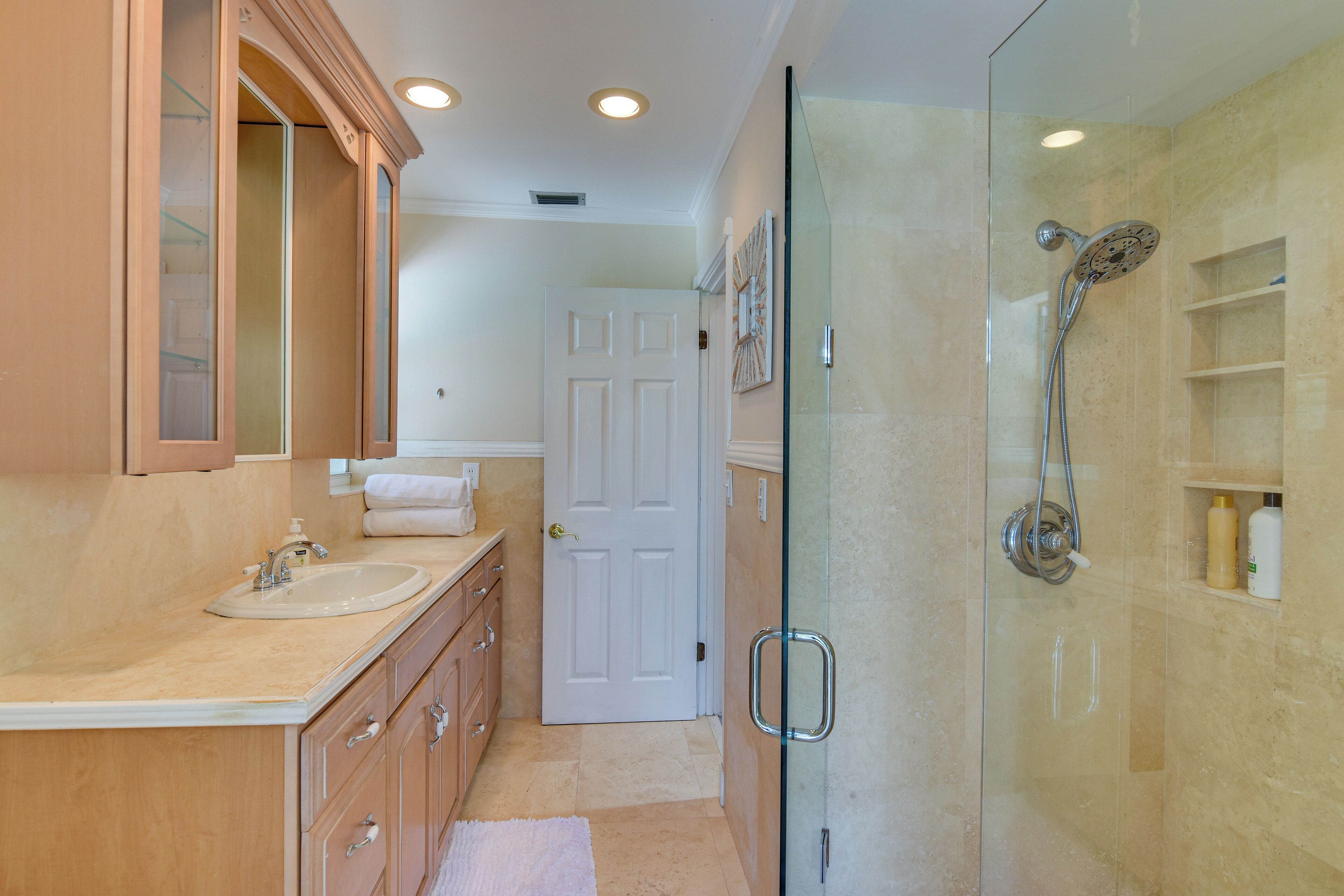 A bathroom with a glass-enclosed shower, a sink, and a mirror.
