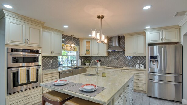 A modern kitchen with stainless steel appliances, white cabinetry, and a central island with bar stools. - 16 Mi to Fort Lauderdale: Florida Escape w/ Pool! (Plantation)