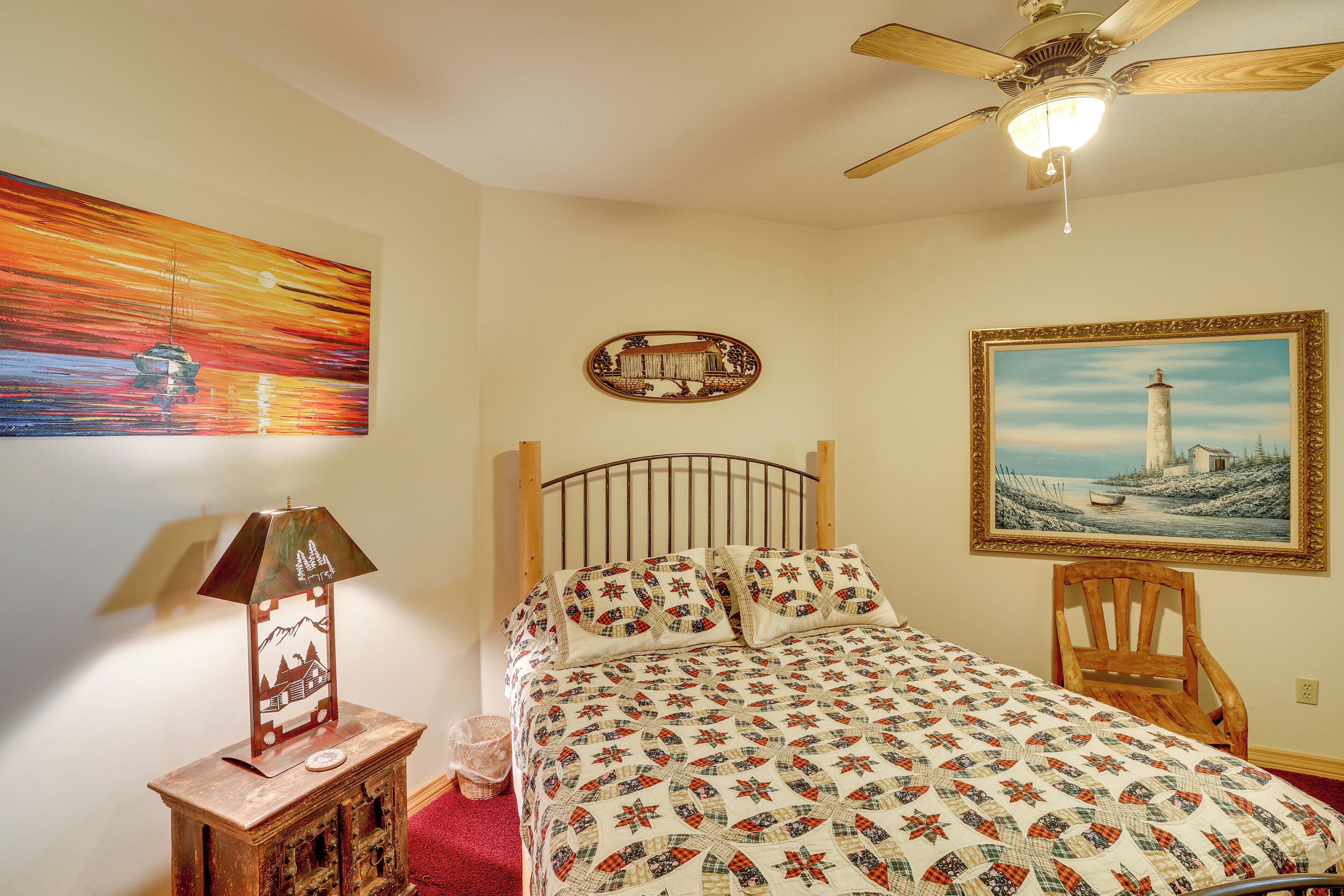 A bedroom with a bed, a nightstand, a lamp, a chair, and two paintings on the walls.