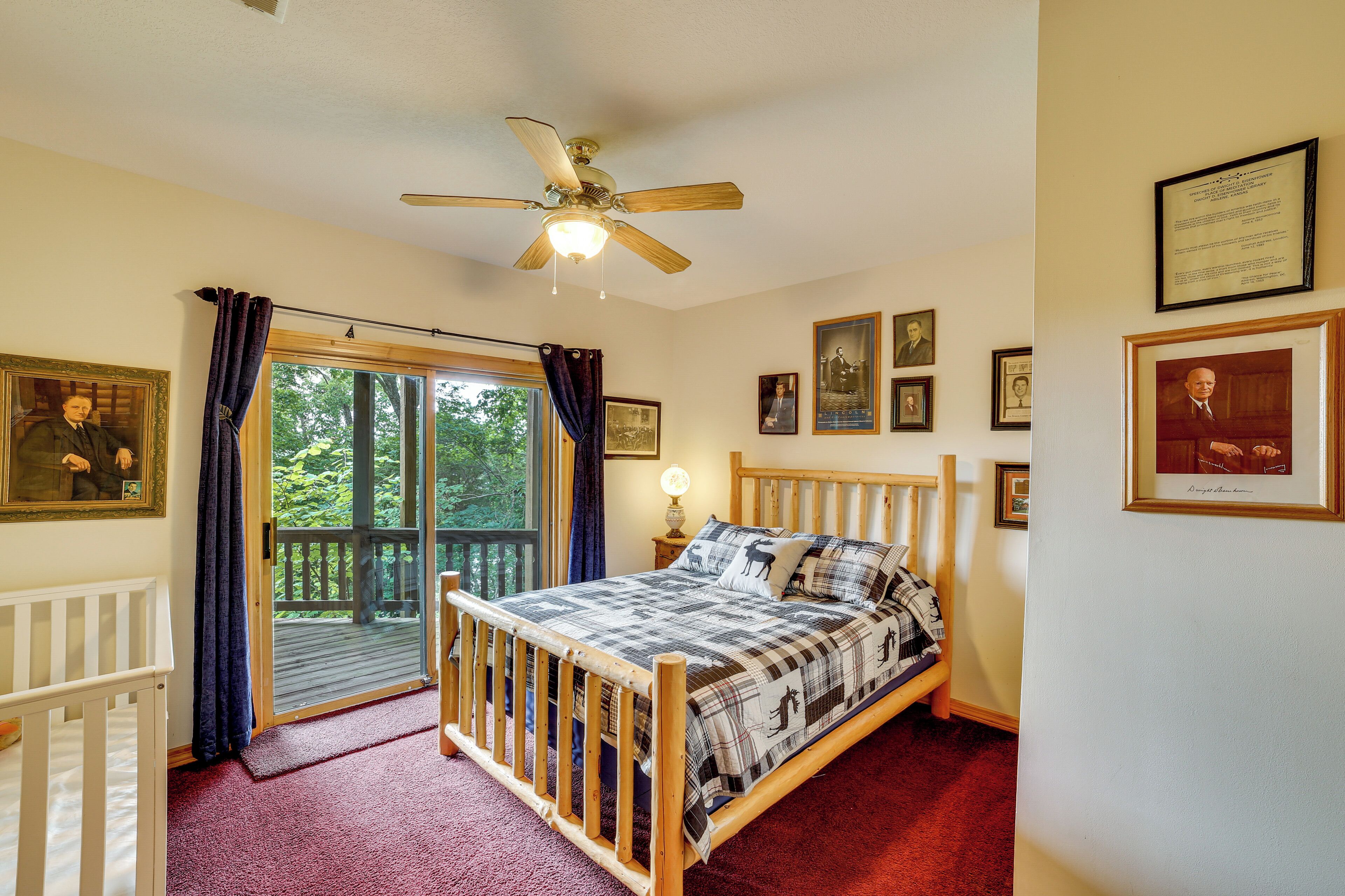A bedroom with a bed, a ceiling fan, a window with curtains, and framed pictures on the wall.