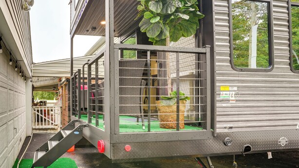 A modern RV with a covered porch, a large potted plant, and a small outdoor seating area. - 10 Mi to Leesylvania & River: Sleek Mobile Home (Woodbridge)