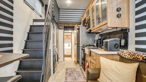 A compact kitchen with modern appliances, a dining area with a table, and a staircase leading to another room. - 10 Mi to Leesylvania & River: Sleek Mobile Home (Woodbridge)