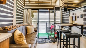 A compact living space with a sofa, a small kitchen area, and a balcony. - 10 Mi to Leesylvania & River: Sleek Mobile Home (Woodbridge)