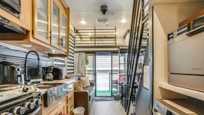 A compact kitchen with a stove, sink, and modern appliances. There is a small seating area with a couch and a window. - 10 Mi to Leesylvania & River: Sleek Mobile Home (Woodbridge)