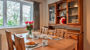 Et spiseområde med et træbord dækket til morgenmad, inklusive croissanter og kaffekopper.