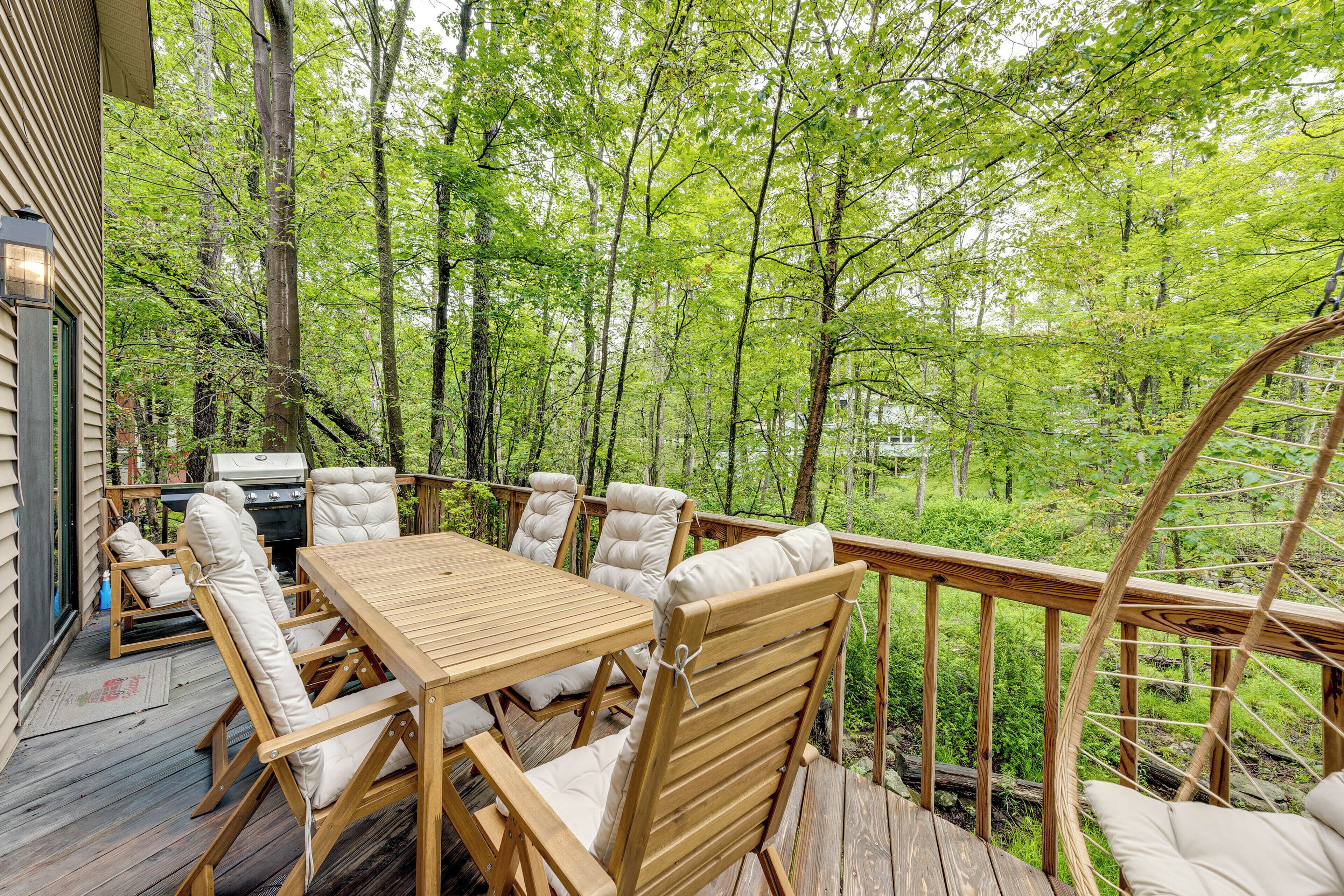 A wooden deck with a table and chairs, surrounded by trees.