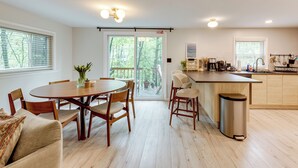 A modern kitchen with wooden cabinets, a dining area with a round table and chairs, and a large sliding glass door leading to a deck. - Lake Access at Family-friendly Home in Tobyhanna (Tobyhanna)