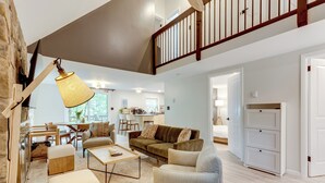 A spacious living room with a high ceiling, a staircase, and a kitchen in the background. - Lake Access at Family-friendly Home in Tobyhanna (Tobyhanna)