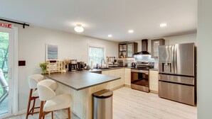 A modern kitchen with a central island, stainless steel appliances, and a view to the outdoors. - Lake Access at Family-friendly Home in Tobyhanna (Tobyhanna)