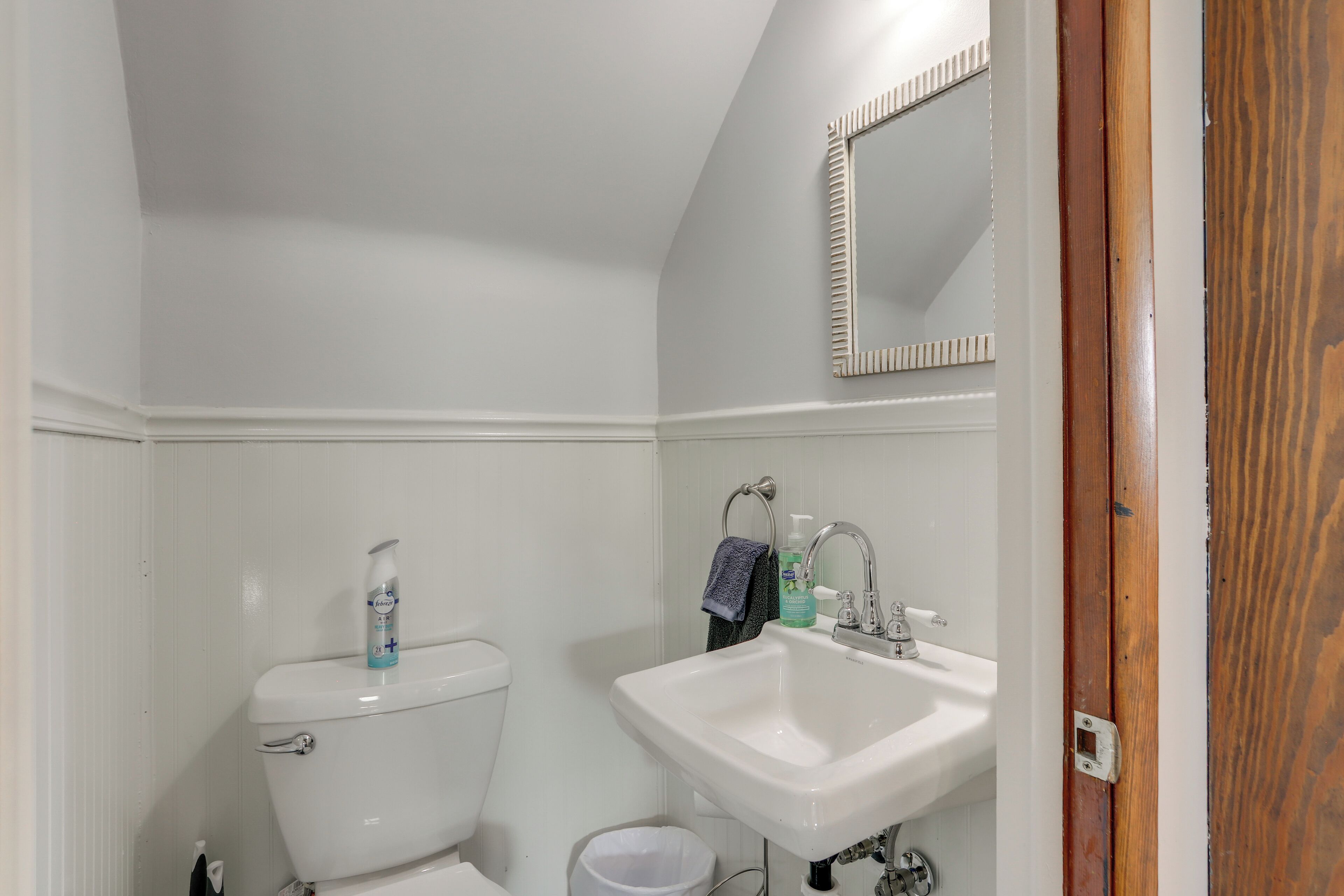 Ein kleines, weißes Badezimmer mit Toilette, Waschbecken und Spiegel.
