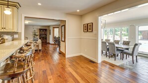 A spacious kitchen with a long countertop and bar stools, a dining area with a table and chairs, and a view through large windows. - Pool, Lake & Patio: Sweeping De Soto Estate (De Soto)