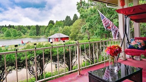 A balcony with a view of a lake, a red building, and an American flag. - Private 5-acre Lake: Pet-friendly Grove City Home (Grove City)