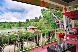 A balcony with a view of a lake, a red building, and an American flag.