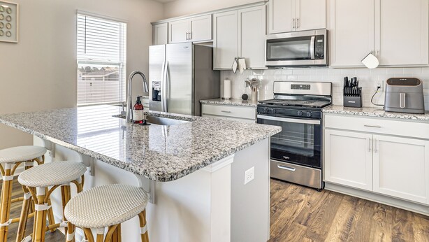 A modern kitchen with white cabinets, a granite countertop, stainless steel appliances, and a bar stool area. - Pool Access, 2 Mi to Main St: Fountain Inn Home! (Fountain Inn)