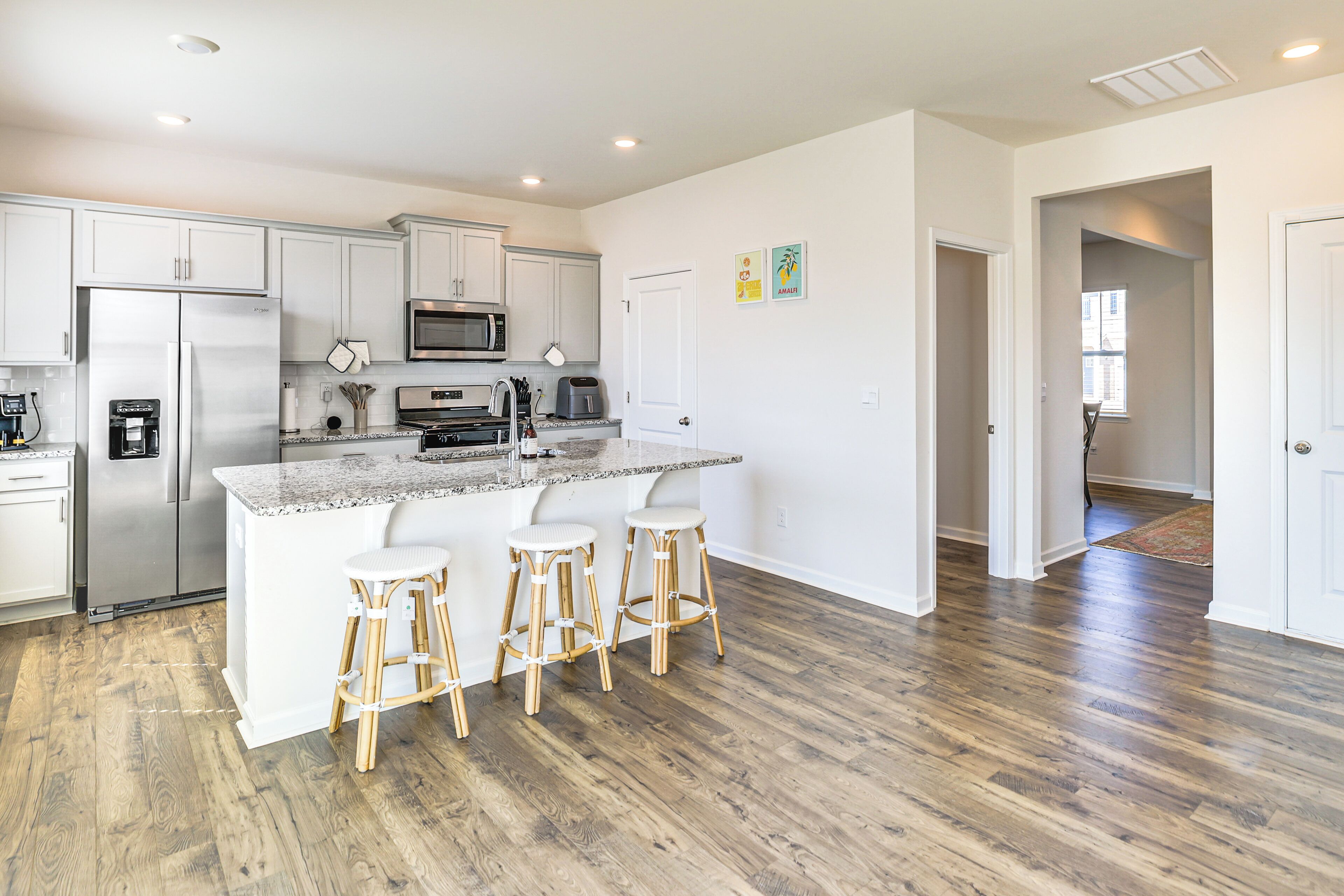 A modern kitchen with white cabinets, stainless steel appliances, and a central island with bar stools.