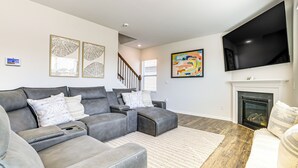 A modern living room with a sectional sofa, a fireplace, and artwork on the walls. - Pool Access, 2 Mi to Main St: Fountain Inn Home! (Fountain Inn)