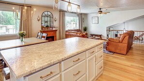 Una cocina con encimera de granito, muebles blancos y una zona de comedor con mesa y sillas.