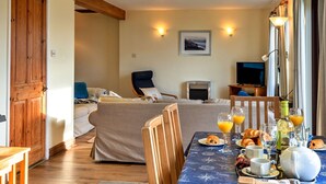 Una habitació acollidora amb un llit, un sofà, una taula de dinar preparada per l'esmorzar i una televisió.