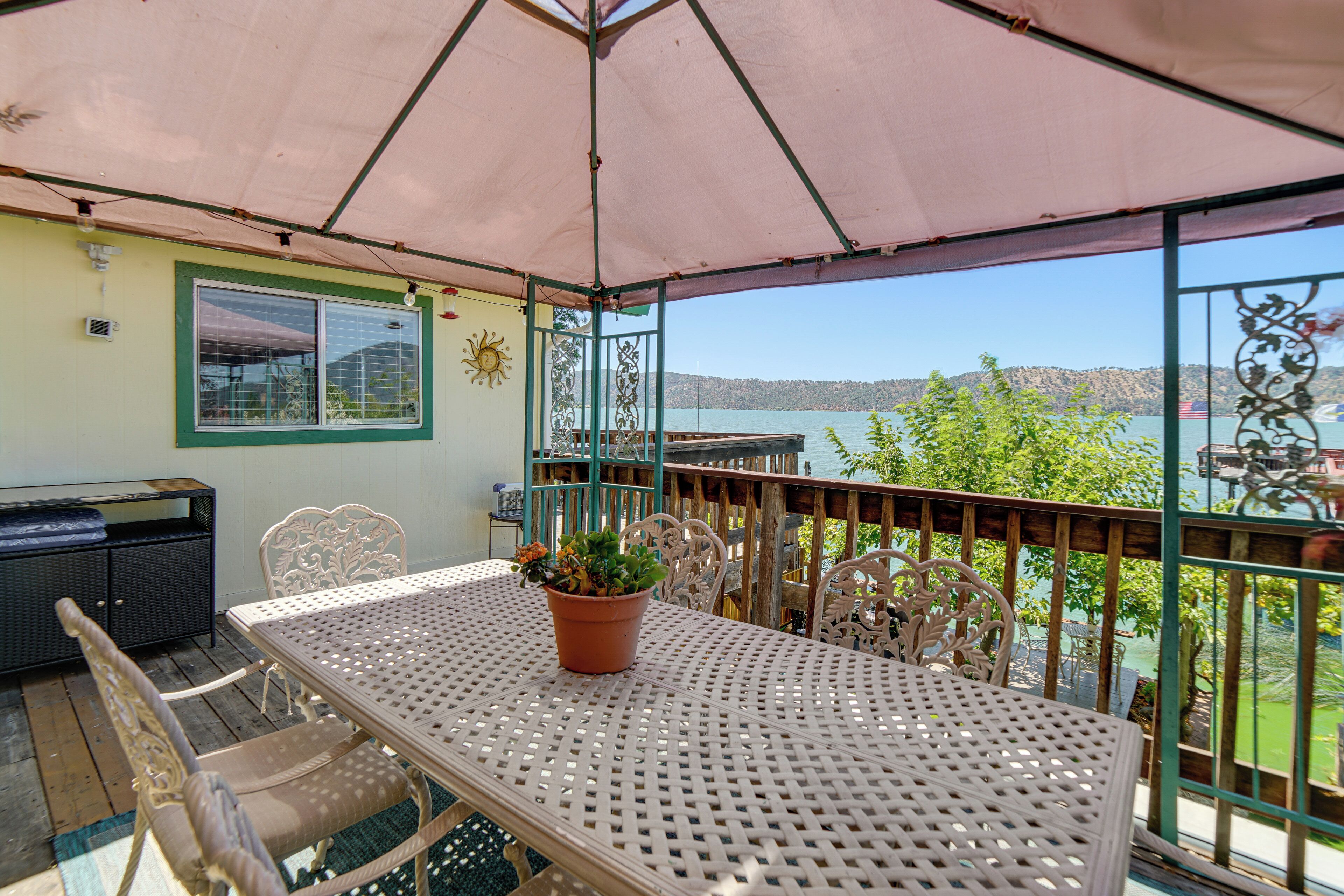 A covered patio with a table and chairs, a potted plant, and a view of a lake.