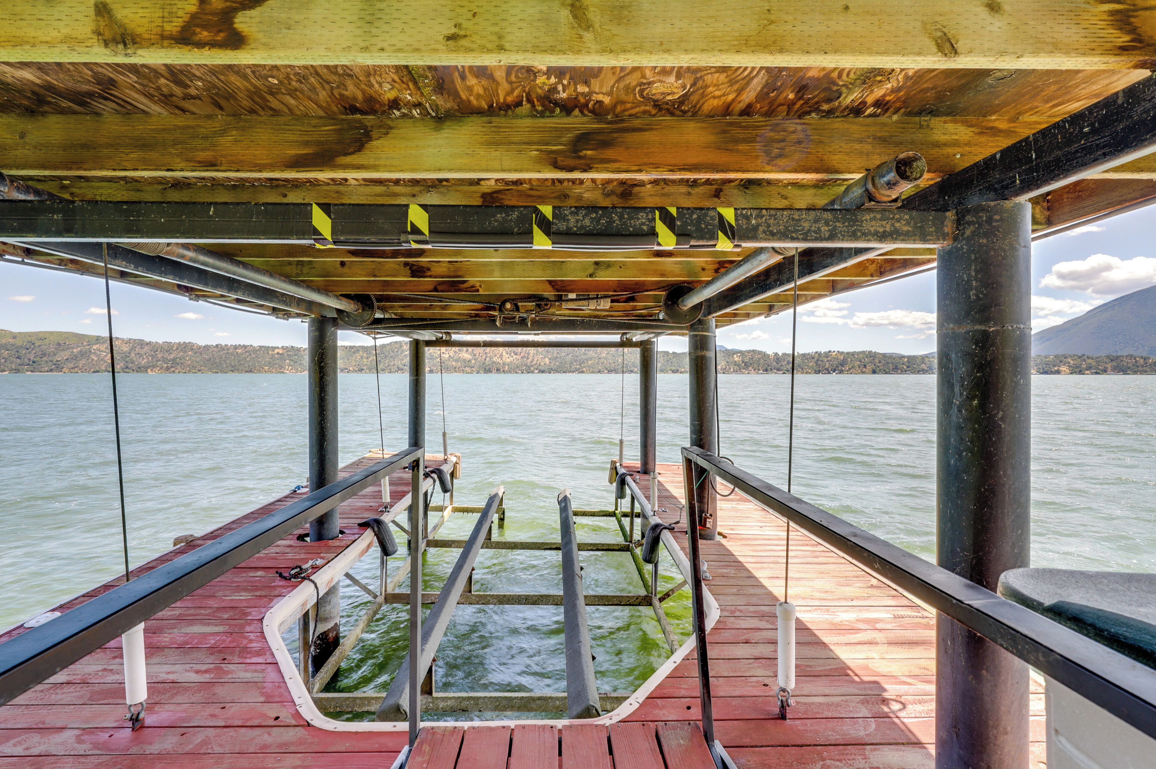 Blick vom Deck eines Bootes mit Holz- und Metallgeländern sowie auf das Wasser und das entfernte Land.