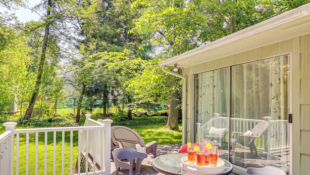 Une terrasse avec des sièges, une table avec des boissons et une vue sur un jardin luxuriant.