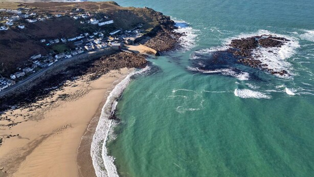 An aerial view of a coastal town with a sandy beach, rocky outcrops, and a lighthouse in the distance. - Wonderful  villa for 3 people with WIFI and pets allowed (Penzance)